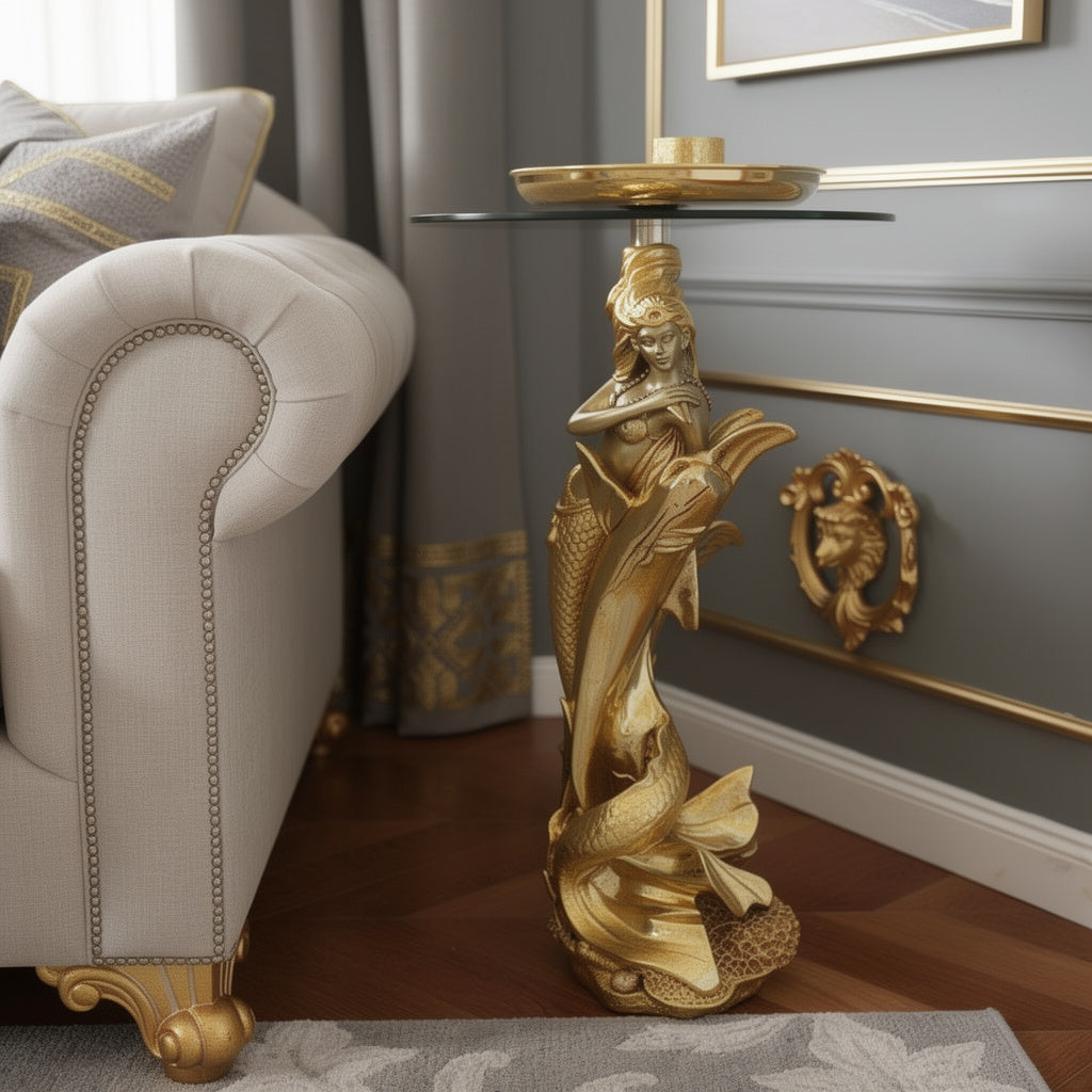 Gold Mermaid Sculptural Glass Side Table lifestyle — 34 inch gold mermaid and dolphin pedestal with round glass top beside cream button-tufted Chesterfield sofa in luxury grey and gold living room with gold wall panelling