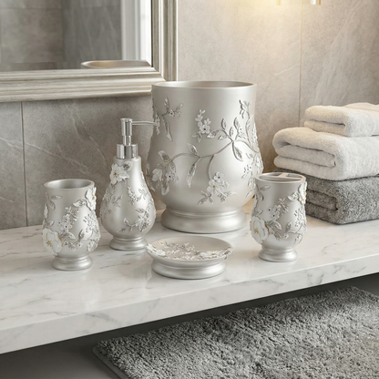 Melrose Yellow accessories set lifestyle — ivory-pearl raised botanical resin accessories on marble vanity counter beside crystal lamp and coordinating grey floral rug in white tile bathroom