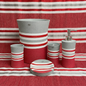Ivanna Beige accessories set on marble vanity — sand-tone stripe waste basket, dispenser, holder and tumbler with coordinating towel and flowers in warm bathroom