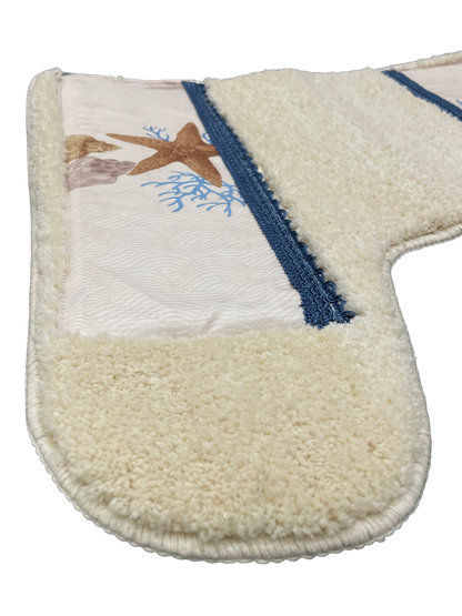 Spa Shell bath rug close-up — plush ivory chenille with starfish coral print inset and navy grosgrain ribbon border detail