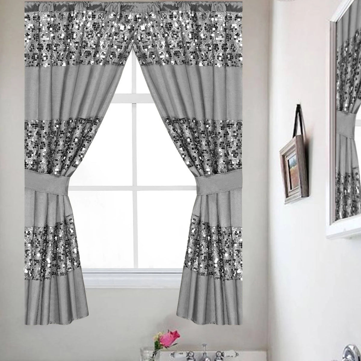 Sinatra Silver window curtain — cool silver-grey fabric with brilliant silver sequin medallion embroidery bands, attached valance and tie-backs in bright bathroom with morning light